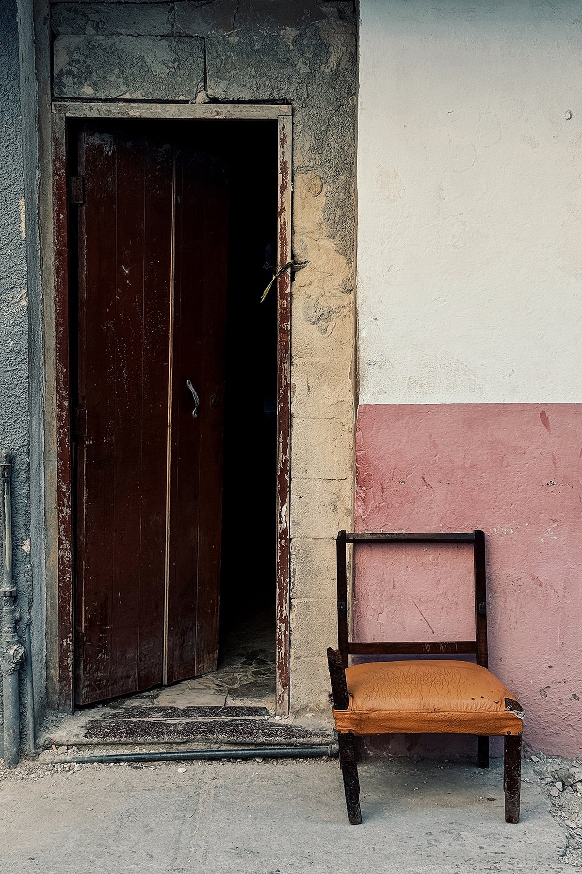 Colorful art print of an orange-seated chair next to a brown door in Cuba.