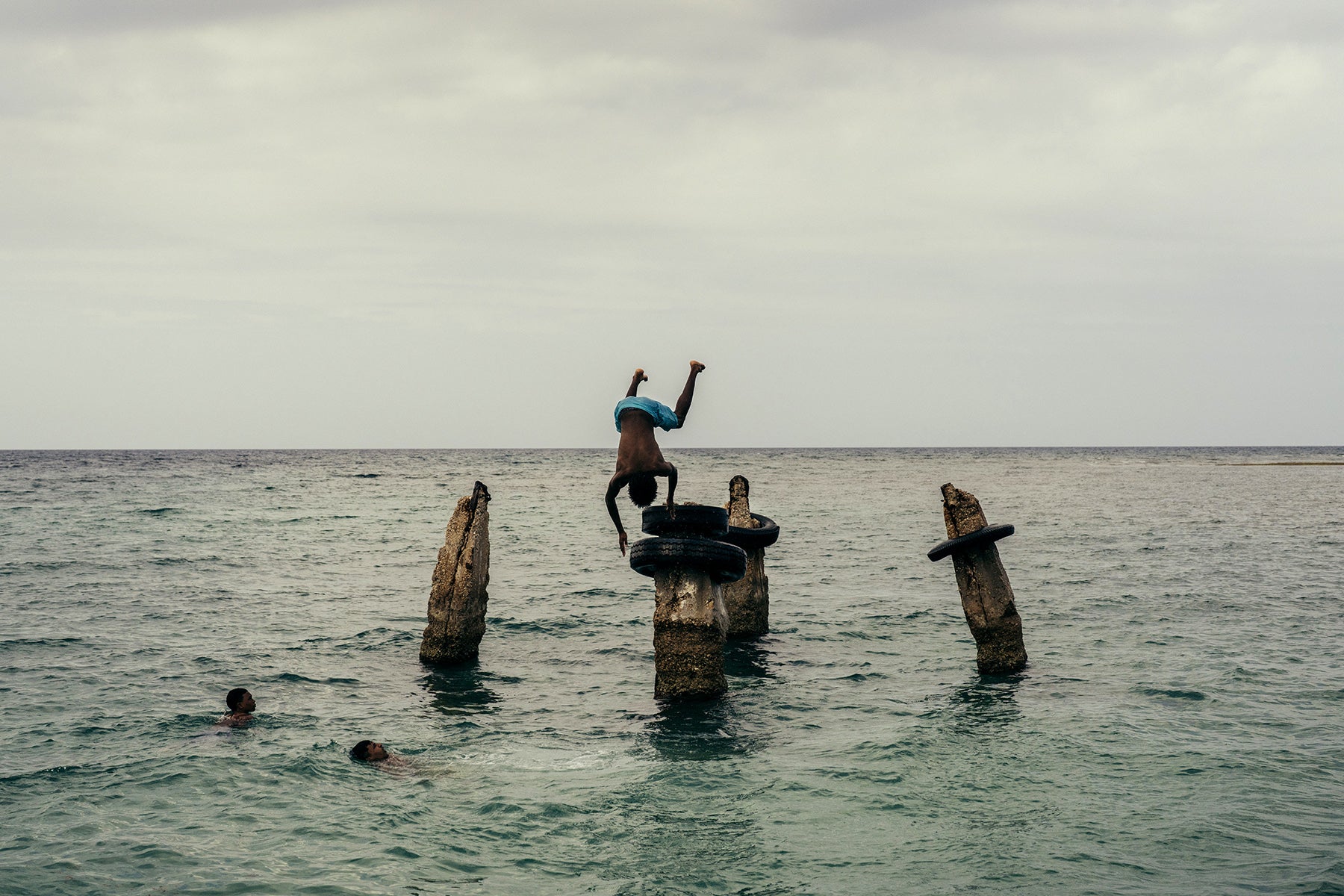 Art print of a person diving off a wooden structure into the ocean with another person swimming nearby in Cuba.