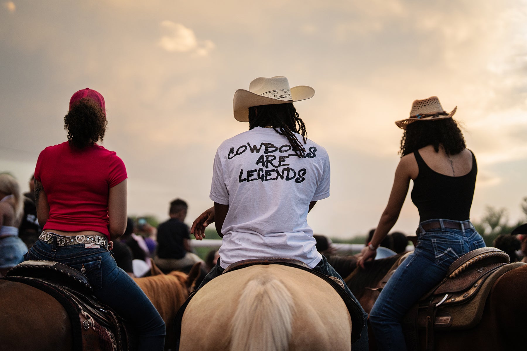 Back view of three cowboys on horses in Boley Oklahoma near sunset.