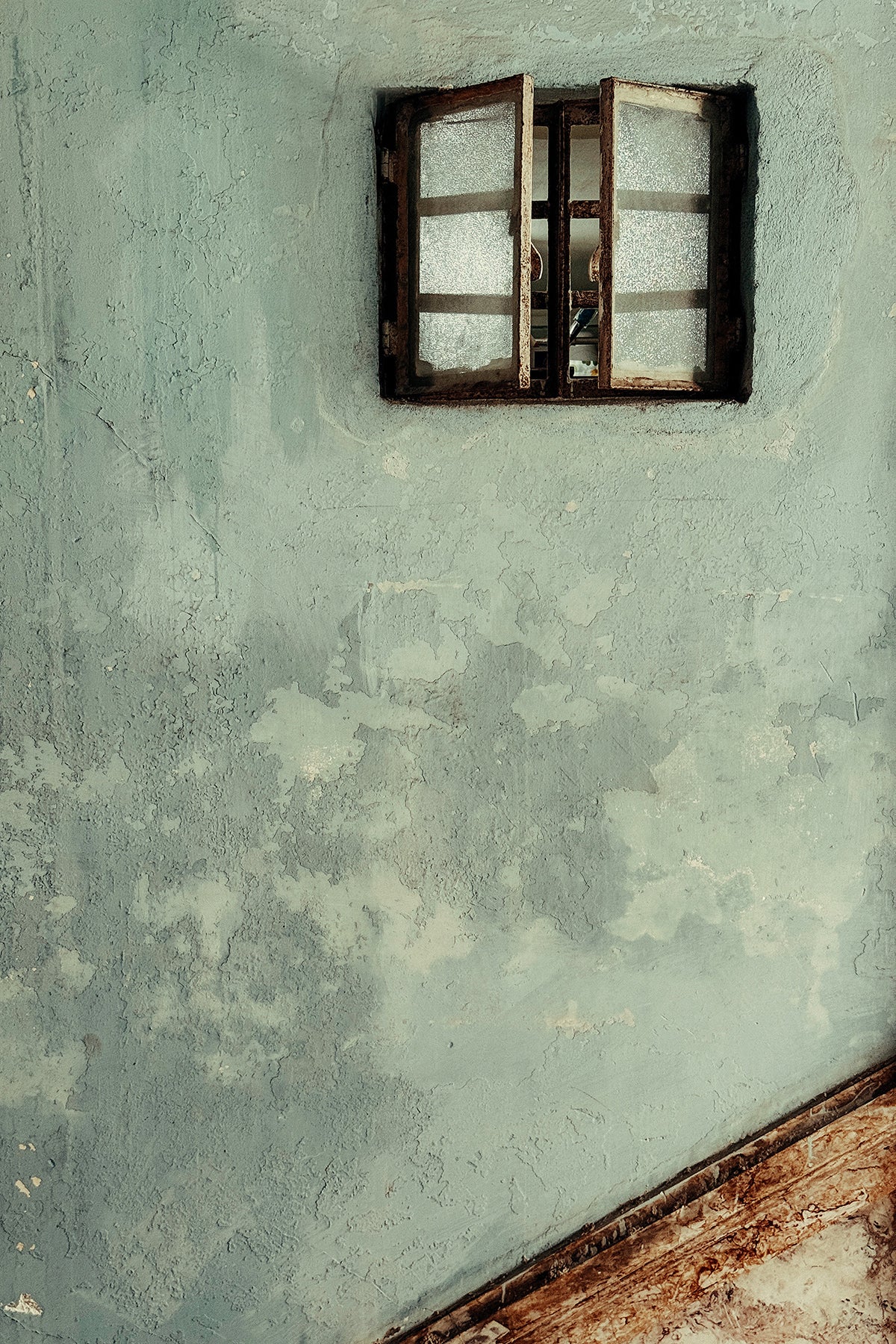 Small window with wooden frame on a textured wall