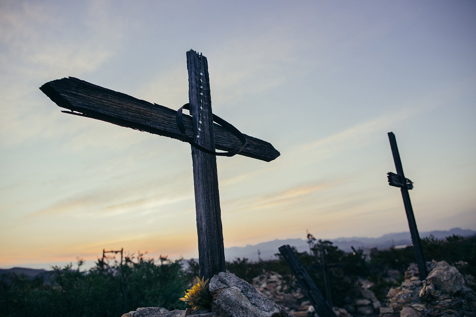 A wooden cross sits atop a burial grave in Terlingua, Texas. Fine art color print.