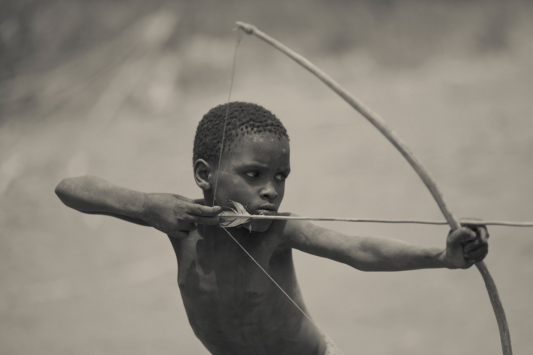 Black and white photo of a Tanzanian child with a bow and arrow